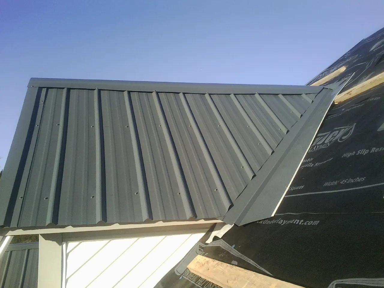 Gray metal roof panels going on over a garage gable in Elkins