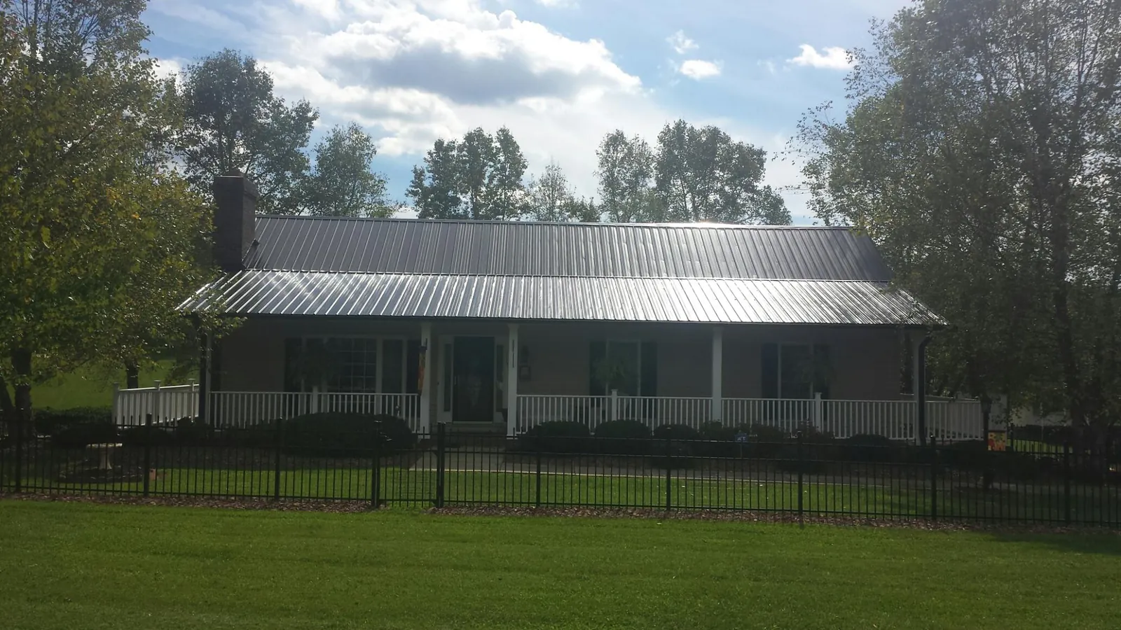 Gray metal roof on a brick ranch with a full width front porch — Gutter Guard Installation work by our crew in Elkins
